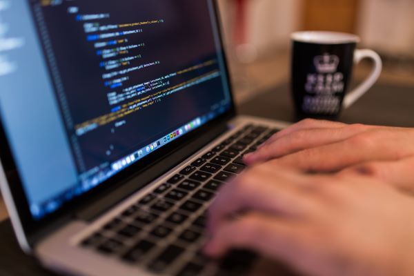 Manos escribiendo código en una computadora portátil