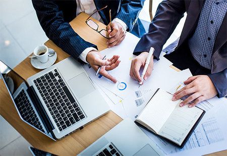 Equipo revisando documentos y gráficos junto a una computadora